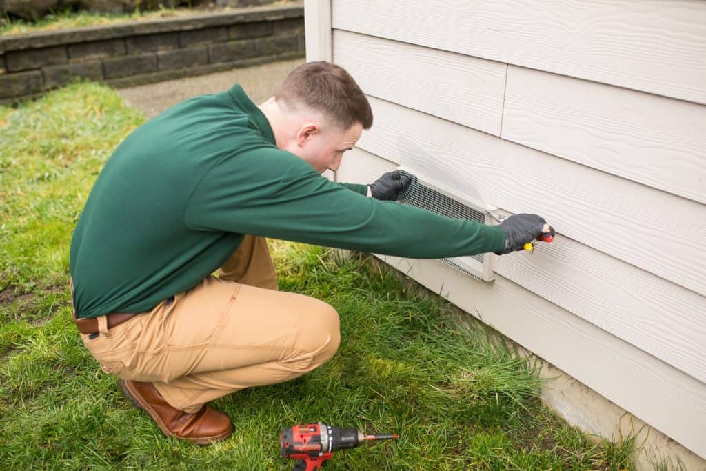 Exterminator inspecting window screen for pests on residential house, pest control services, eco-friendly pest extermination, professional pest inspection, Campbell Natural Pest Control.