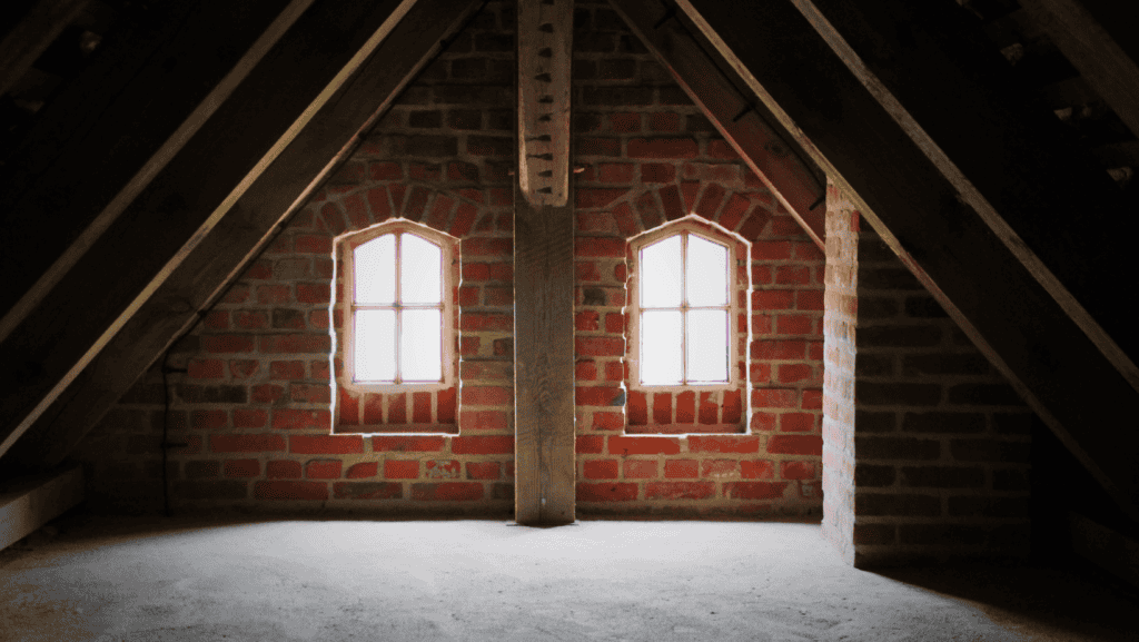 Attic with brick walls and windows in a rustic setting, showcasing attic insulation and structural elements, ideal for highlighting pest control and home maintenance services.