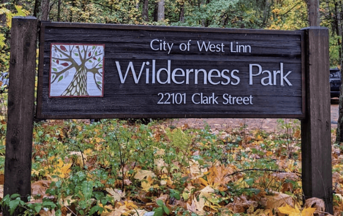 Wilderness Park sign located at 22101 Clark Street in West Linn, surrounded by autumn leaves, highlighting outdoor recreation and community nature spaces.