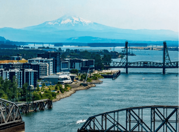 Portland Oregon skyline with Mount Hood in the background, showcasing a vibrant cityscape and river views.
