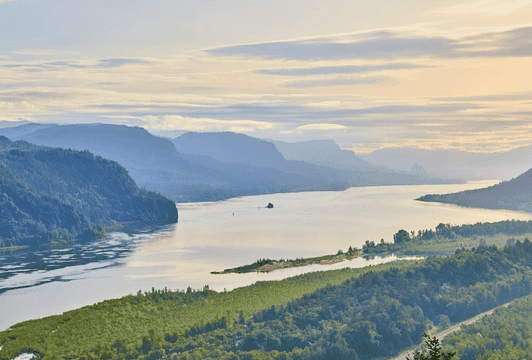 River landscape surrounded by lush green hills and mountains at sunset, emphasizing natural beauty and environmental harmony.